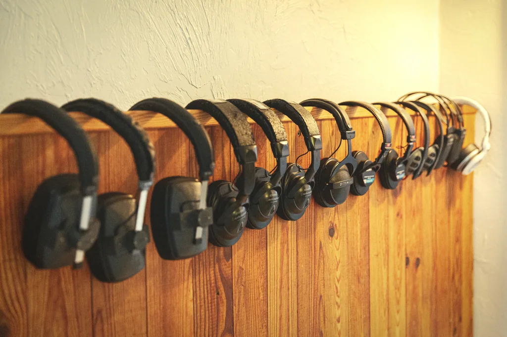 Multiple professional headphones lined up on wooden rail in Limusic residential recording studio in Limoux, southern France