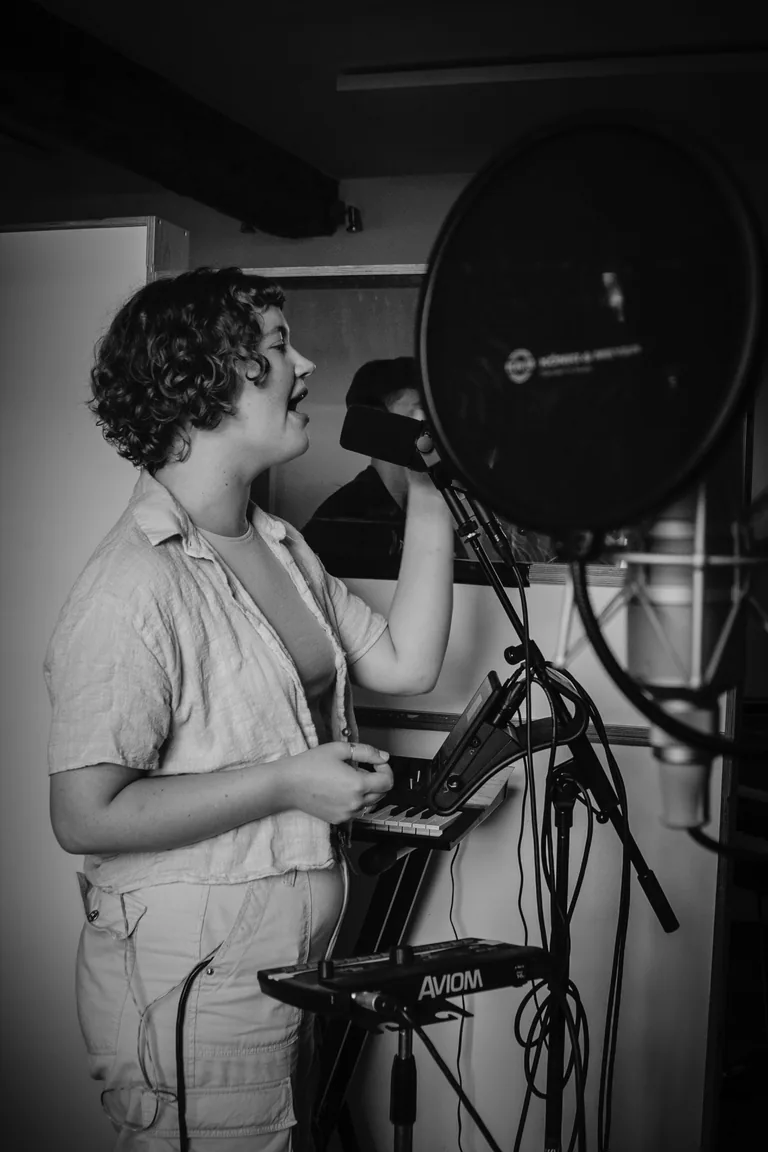 Singer recording vocals with studio microphone and professional audio equipment during recording session at Limusic
