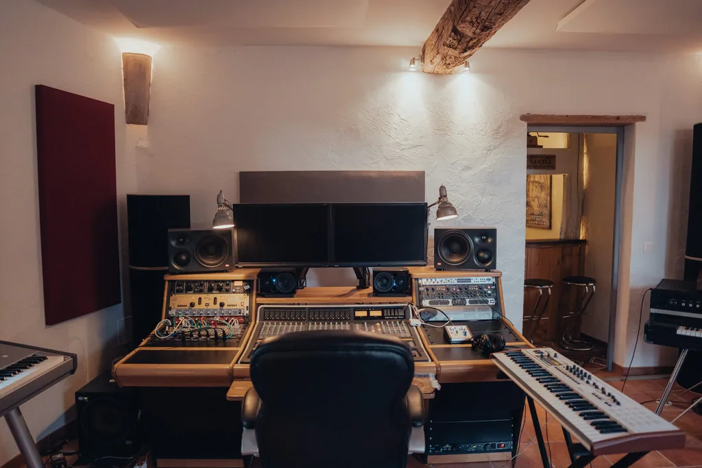 Professional recording studio control room with dual monitors, mixing console, synthesizers, and acoustic treatment at Limusic residential recording studio in Limoux, southern France