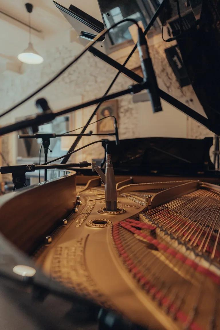 Microphone positioned above grand piano strings in residential recording studio session at Limusic in Limoux, southern France