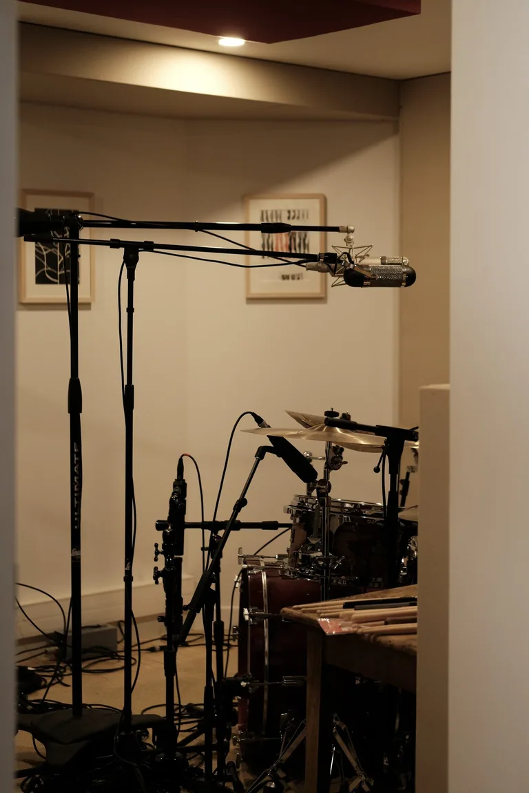 Professional recording booth at Limusic residential studio with condenser microphone, boom arm, and drum kit setup for all-inclusive recording sessions in southern France