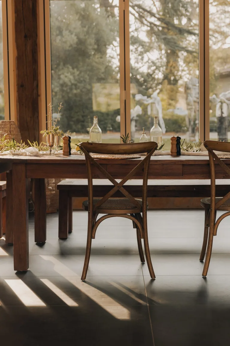 Dining table with wooden chairs overlooking estate grounds at Limusic residential recording studio in Limoux, southern France
