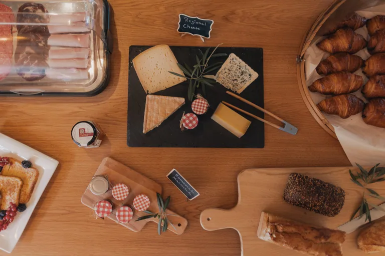 Regional cheese, charcuterie, croissants and bread displayed on wooden table at Limusic all-inclusive studio in Limoux, southern France