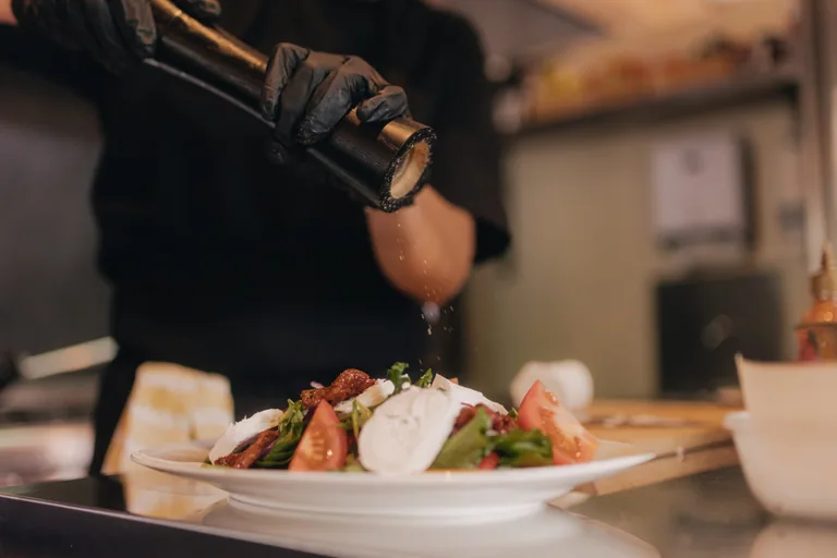 Chef plating fresh regional dish with sauce during recording session catering at Limusic studio