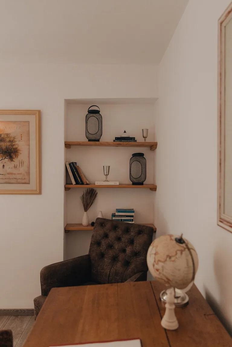 Cozy studio lounge with wooden shelving, dark armchair, and decorative accents at Limusic residential recording studio in Limoux