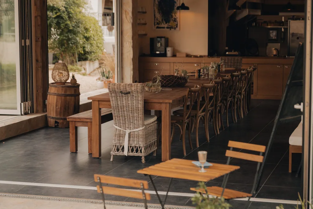 Dining area at Limusic Residential Recording Studio in Limoux with wooden tables, wicker chairs, and open terrace overlooking the Occitanie estate