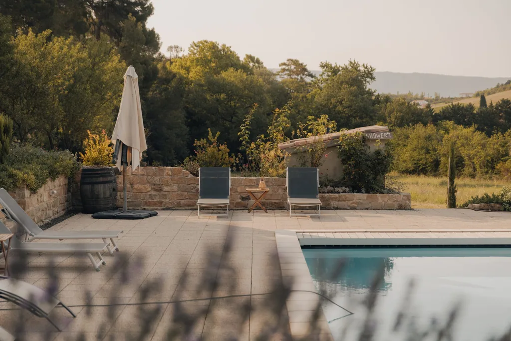 Poolside terrace at Limusic residential recording studio in Limoux, Occitanie, with loungers and umbrella overlooking the Domaine de Bourigeols estate grounds