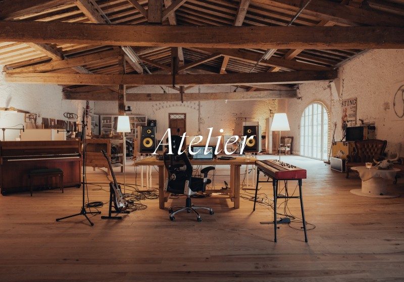 Spacious recording studio live room with wooden beams, piano, synthesizer, and professional audio equipment at Limusic artist retreat in southern France