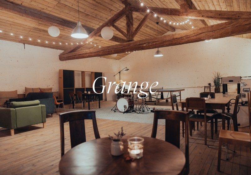 Spacious Grange live room with drum kit, wooden beams, seating area, and warm lighting at Limusic recording studio in southern France